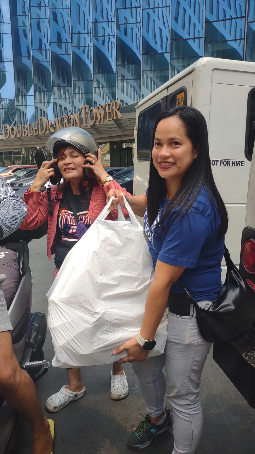 A smiling ministry volunteer holding a large bag of supplies on a city street