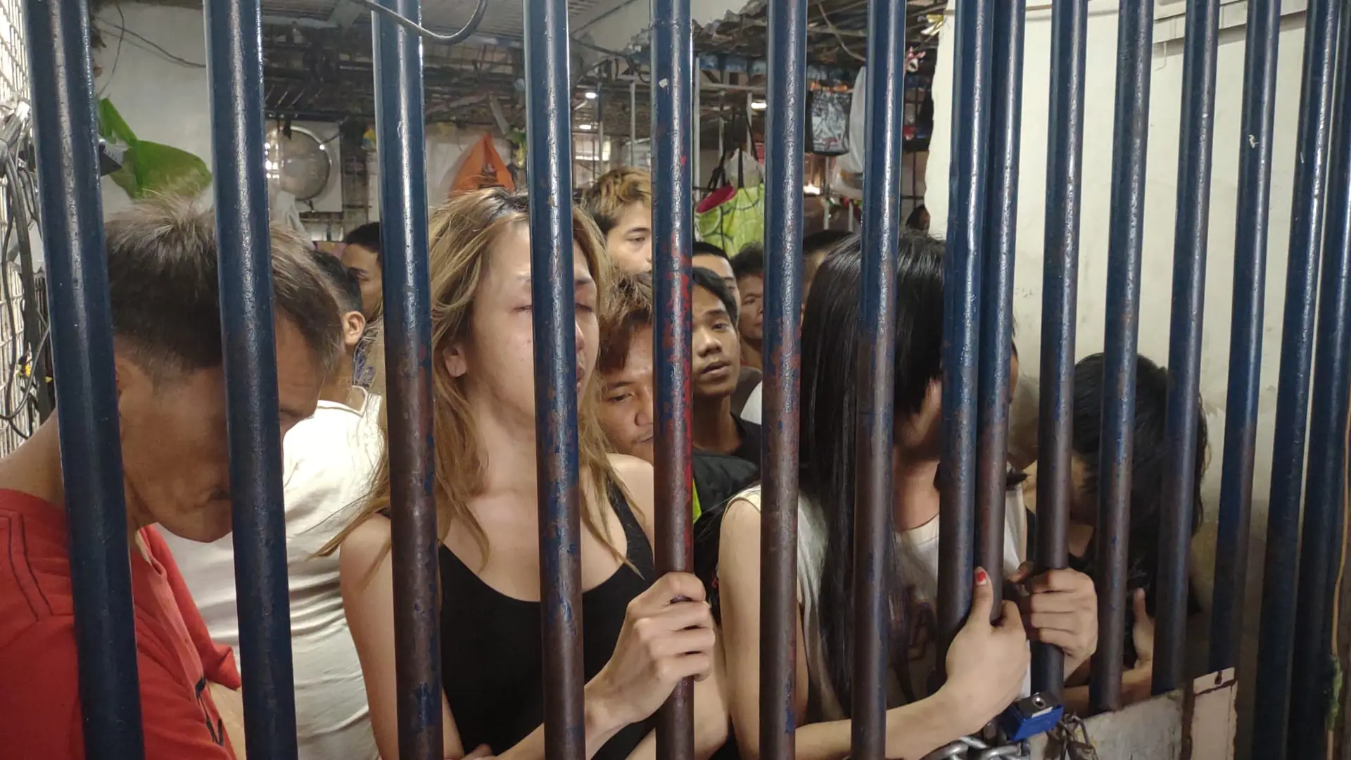 People pressed against the bars of a crowded jail cell in the Philippines