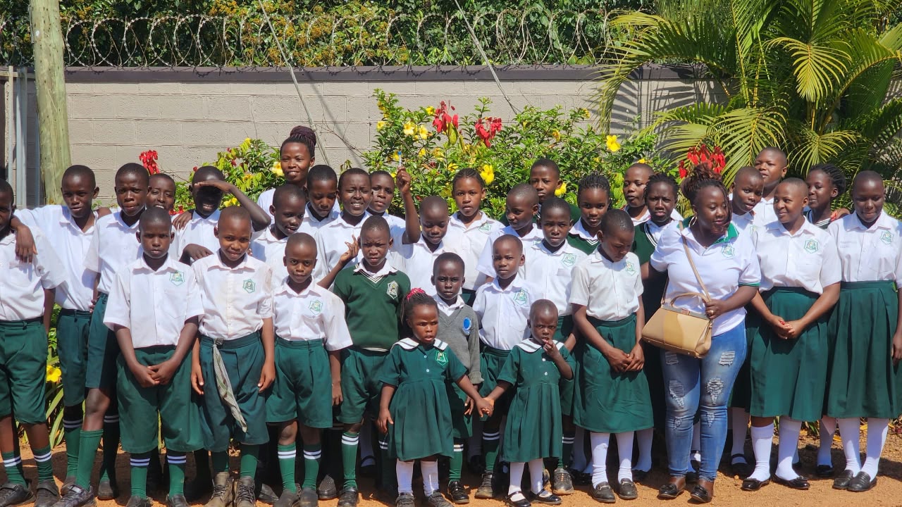 Pupils in green uniforms with a teacher in Uganda