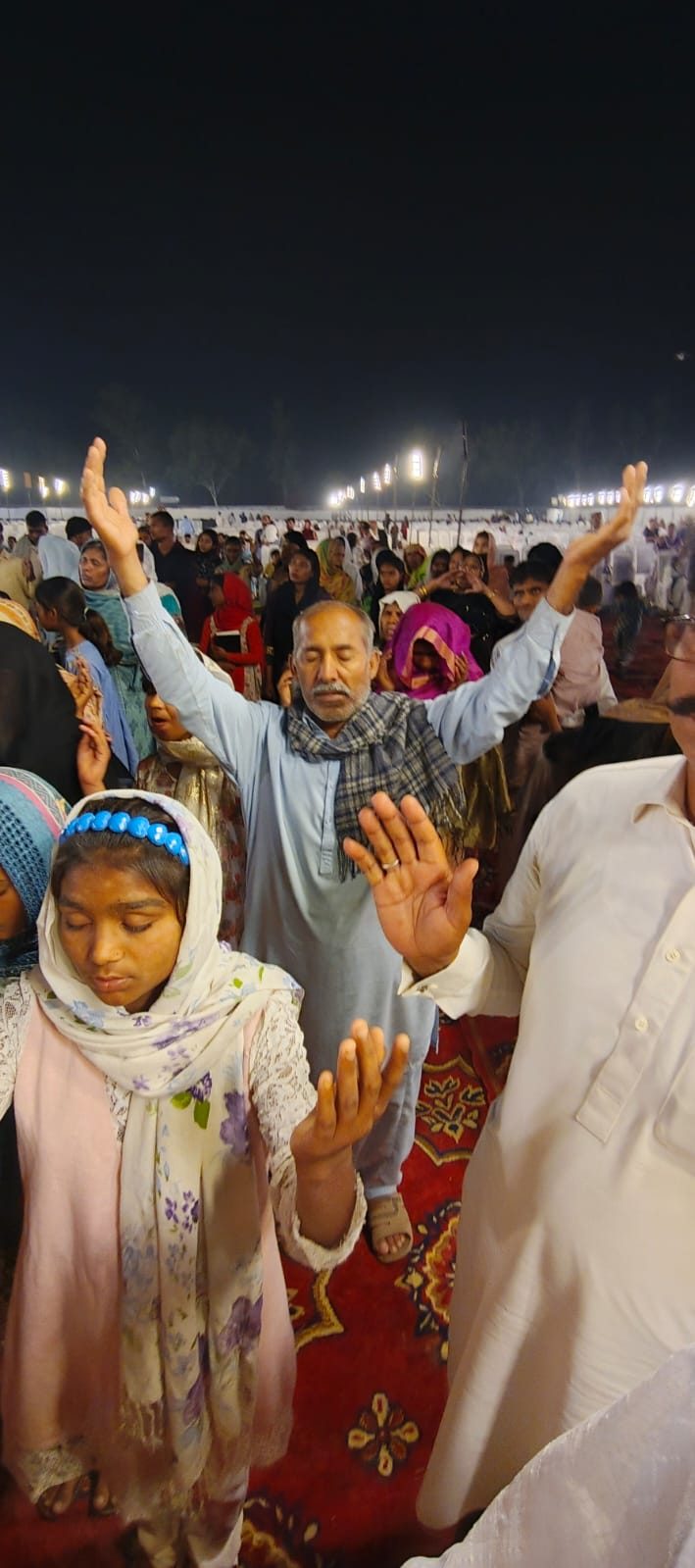 A man lifting his hands in worship at a prayer gathering in Raiwind